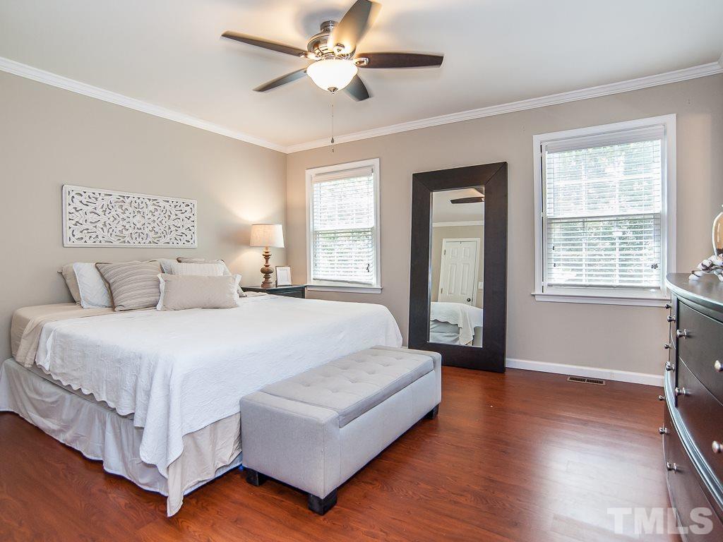 7605 Elliot Drive Raleigh, NC 27613 - Photo 8 of 22 a spacious bedroom with a large bed and a chandelier