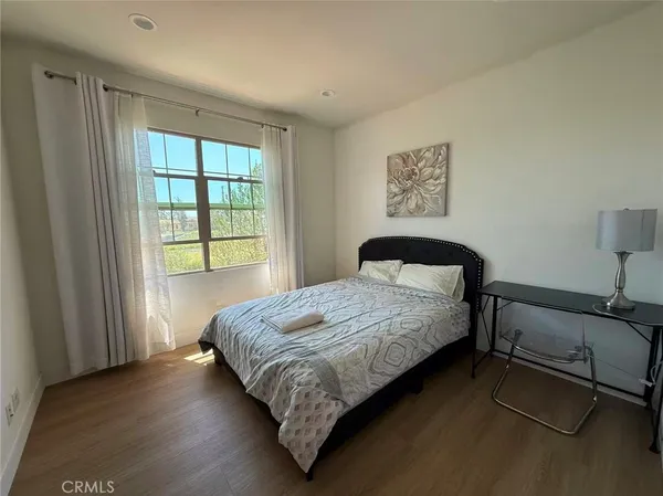 a bedroom with a bed wooden floor and window