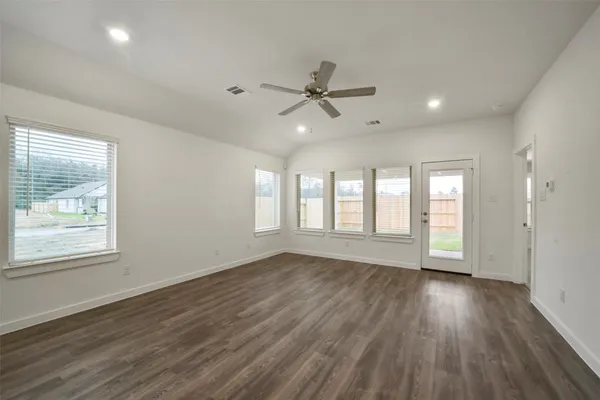 a view of an empty room with wooden floor and a window
