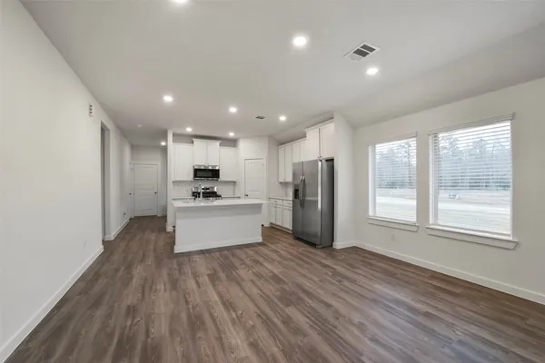 a large kitchen with a lot of white cabinets and stainless steel appliances