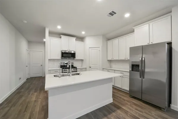 a kitchen with a refrigerator a stove top oven a sink and cabinets