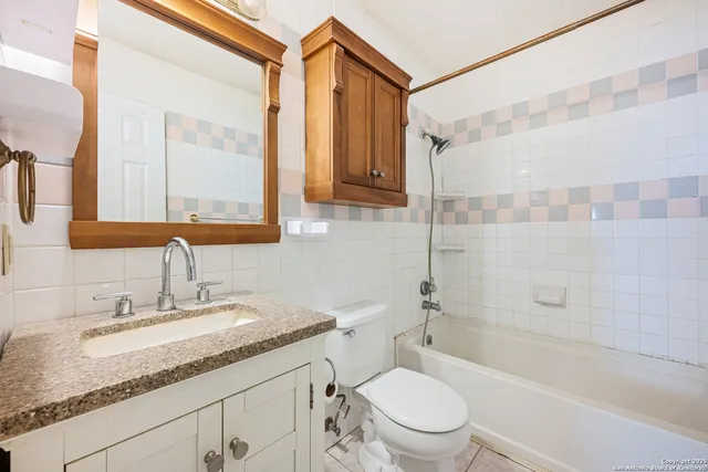 a bathroom with a granite countertop sink a toilet and shower