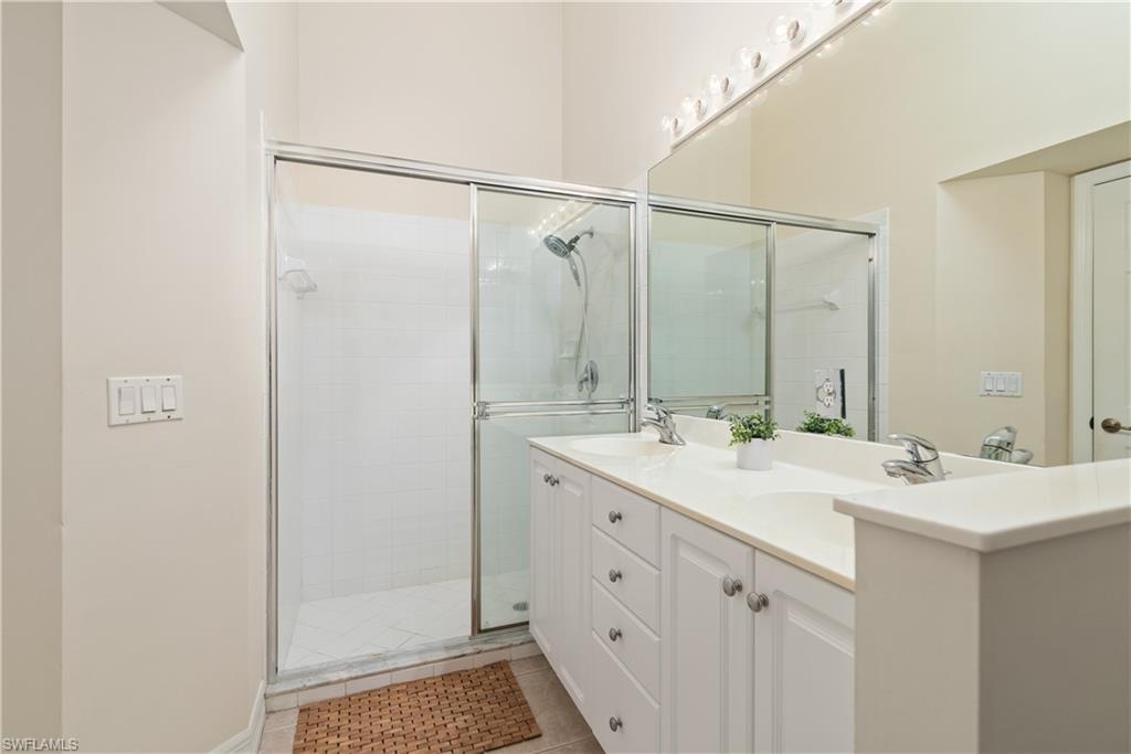 15079 Sterling Oaks Drive Naples, FL 34110 - Photo 13 of 29 a bathroom with a shower sink vanity and mirror
