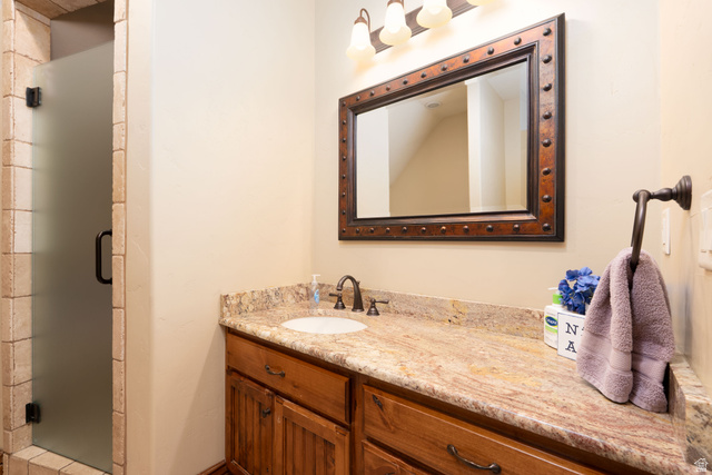 687 South 2080th Street East Springville, UT 84663 - Photo 58 of 149 Bathroom featuring a single vanity with a stone countertop, an undermount sink, and wood-finish cabinetry