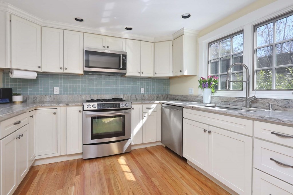 10 Beverly Road Newton, MA 02461 - Photo 8 of 19 a kitchen with granite countertop a stove a sink dishwasher and a microwave oven with white cabinets