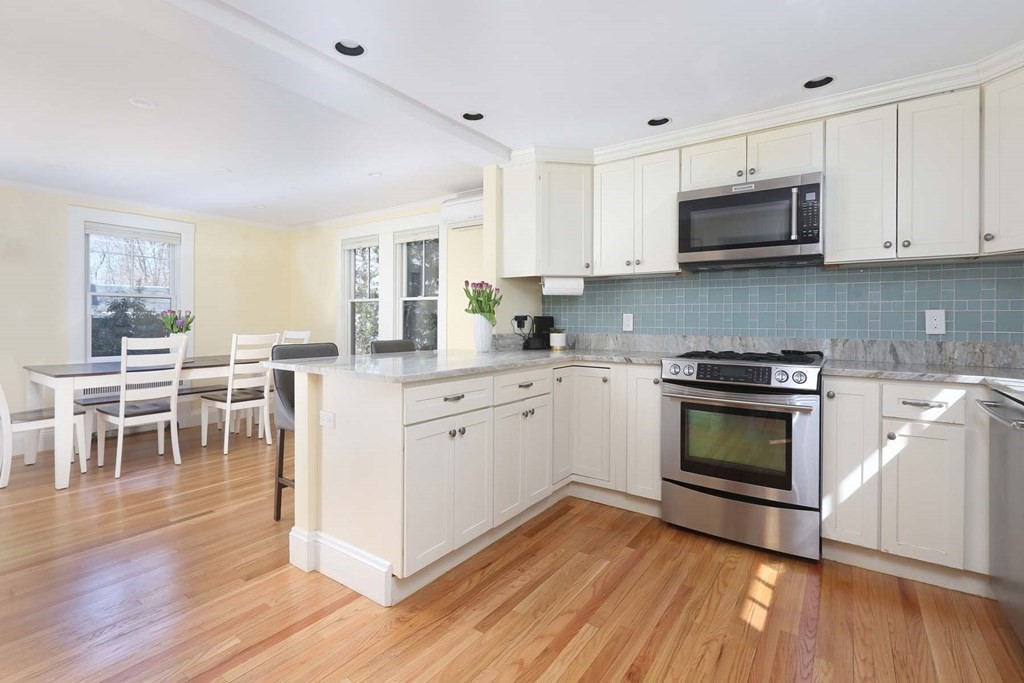 10 Beverly Road Newton, MA 02461 - Photo 9 of 19 a kitchen with stainless steel appliances a stove a sink dishwasher a microwave oven and a dining table with wooden floor