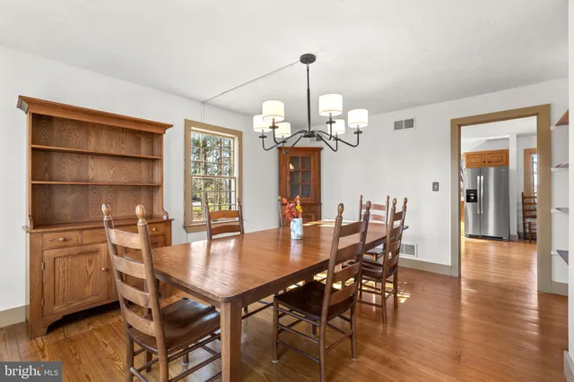 a dining room with wooden floor a chandelier a wooden table and chairs