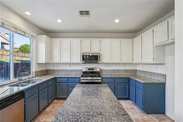 a kitchen with kitchen island granite countertop a sink stove and cabinets