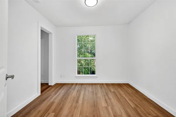 a view of a room that has wooden floor and window