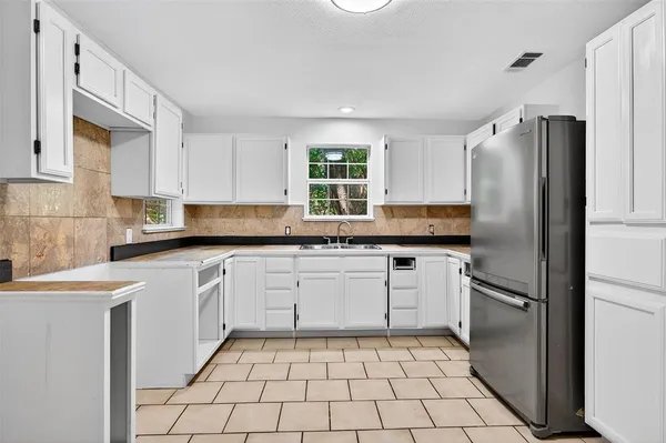 a kitchen with granite countertop stainless steel appliances a refrigerator sink and cabinets
