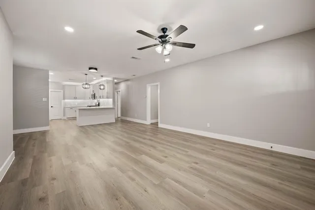 a view of a livingroom with a ceiling fan wooden floor and a ceiling fan