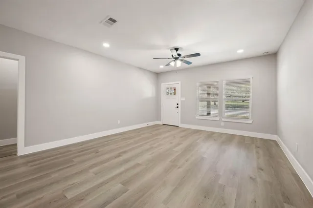a view of an empty room with a window and wooden floor