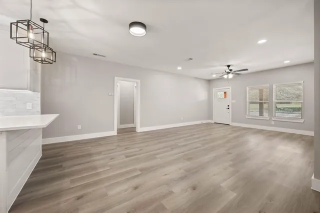 a view of an empty room with wooden floor and windows