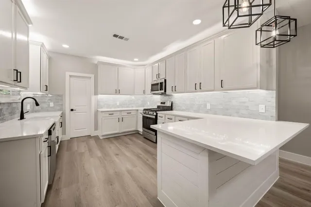 a kitchen that has a lot of cabinets in it and wooden floors
