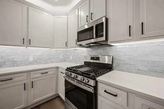 a kitchen with stainless steel appliances white cabinets and stove
