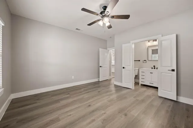 an empty room with wooden floor and a ceiling fan