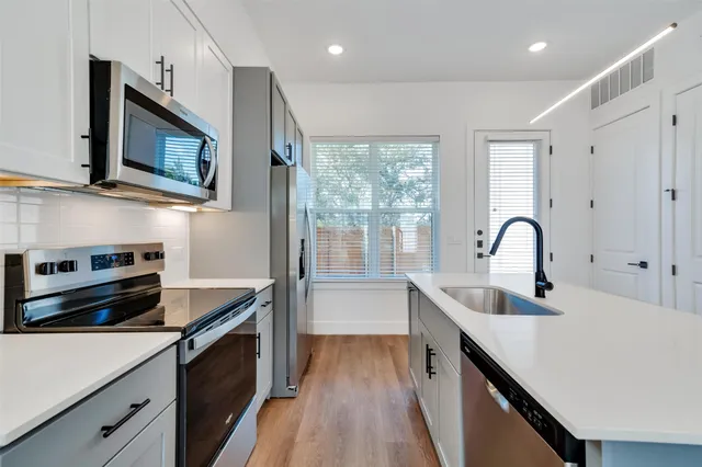 a kitchen with kitchen island a sink appliances cabinets and a window