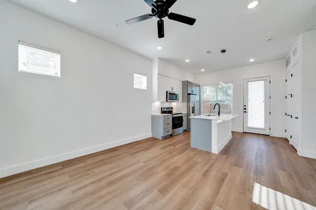 a large white kitchen with wooden floor and a window