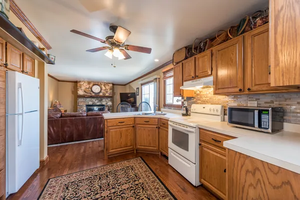 a kitchen with stainless steel appliances granite countertop a refrigerator a sink dishwasher a stove and white cabinets with wooden floor