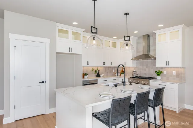 a kitchen with stainless steel appliances kitchen island granite countertop a sink a refrigerator and chairs