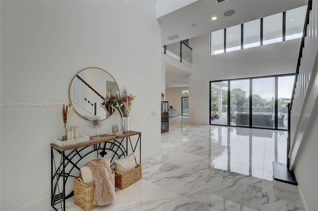 a view of a hallway with a large window and kitchen view