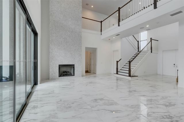 a large white kitchen with a large counter top a sink stainless steel appliances and cabinets