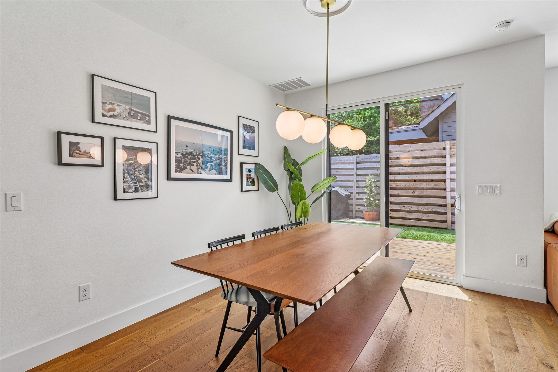 1706 Perez Street, Unit 1 Austin, TX 78721 - Photo 10 of 36 Hardwood floors and a modern light fixture enhance this well-lit dining area, opening to a private patio.