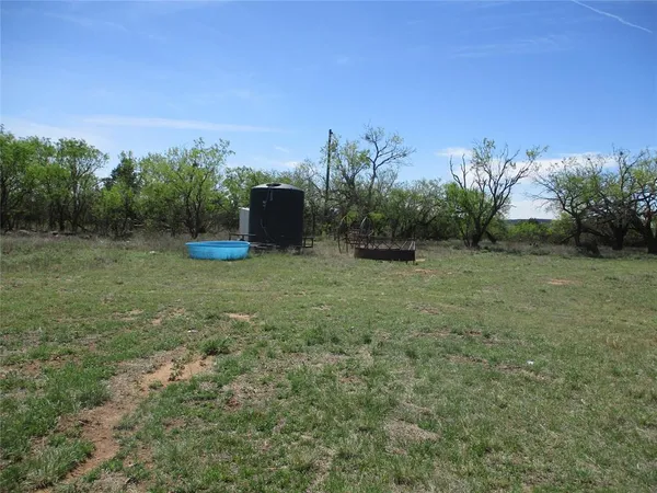 a view of a field with trees in background