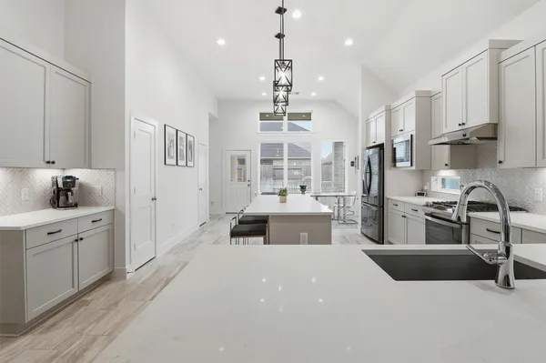 a large kitchen with kitchen island a large counter space a sink stainless steel appliances and cabinets