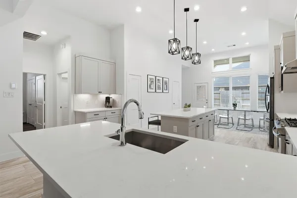 a kitchen with stainless steel appliances a sink dishwasher a refrigerator and a dining table with wooden floor