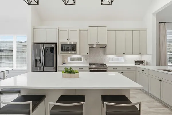 a kitchen with stainless steel appliances a stove a sink and white cabinets