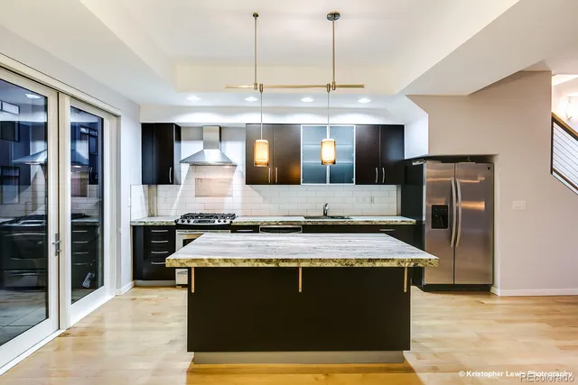 a kitchen with a stove kitchen island a refrigerator wooden floor and a view of living room