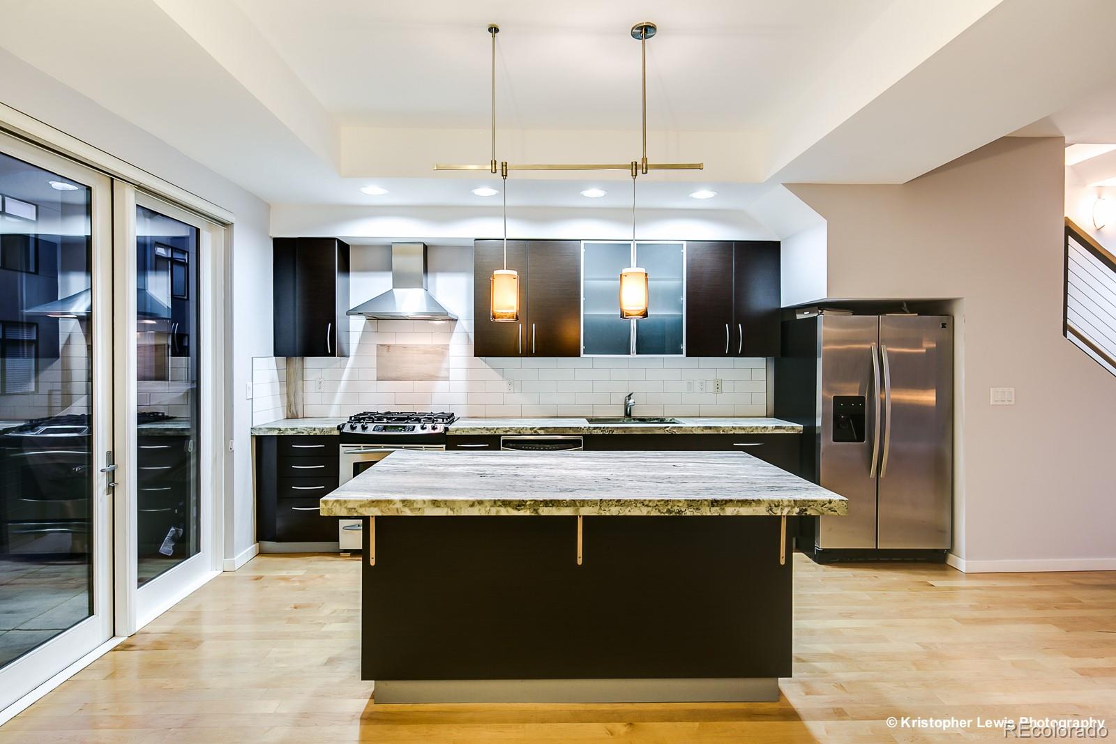 1400 Little Raven Street, Unit B Denver, CO 80202 - Photo 14 of 35 a large kitchen with stainless steel appliances granite countertop a sink counter space and wooden floor
