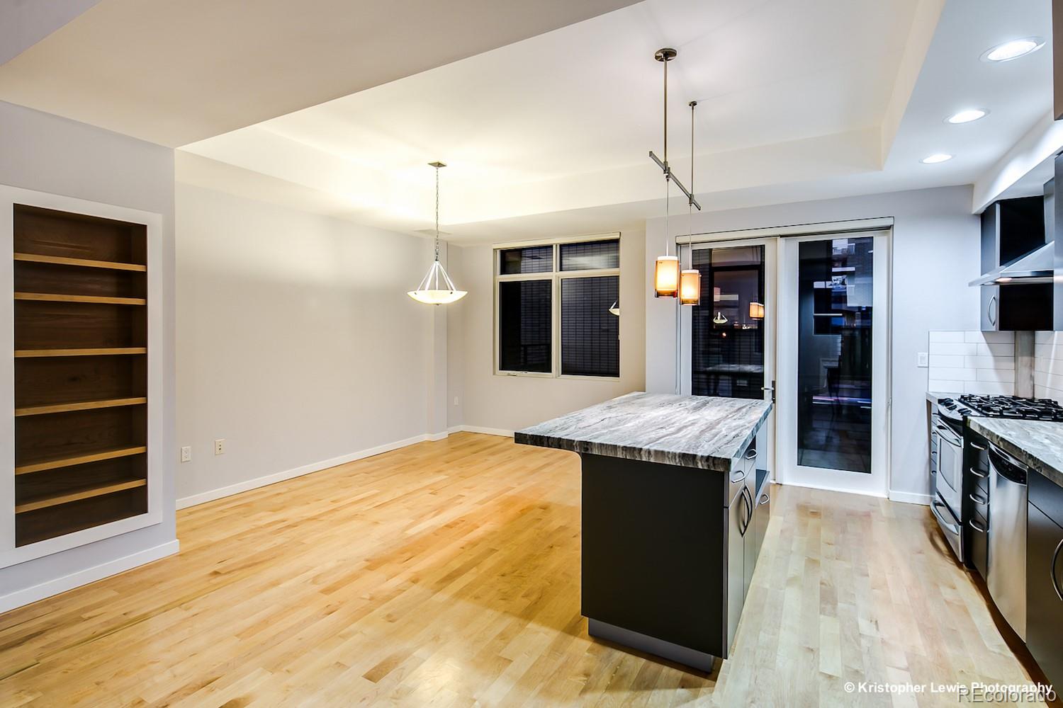 1400 Little Raven Street, Unit B Denver, CO 80202 - Photo 17 of 35 a kitchen with stainless steel appliances kitchen island granite countertop a refrigerator a stove and a sink with wooden floor