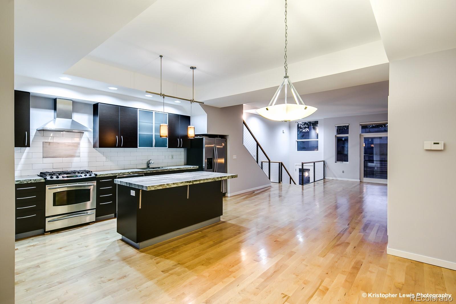 1400 Little Raven Street, Unit B Denver, CO 80202 - Photo 18 of 35 a large kitchen with stainless steel appliances granite countertop a stove and a view of living room