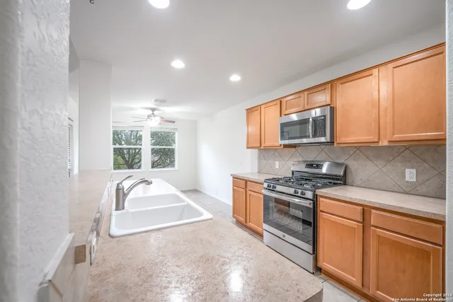 a kitchen with stainless steel appliances granite countertop a stove a sink and a microwave