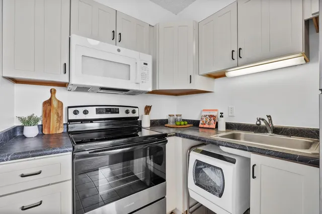 a kitchen with granite countertop white cabinets and white appliances