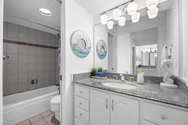 a bathroom with a granite countertop sink mirror toilet and bathtub