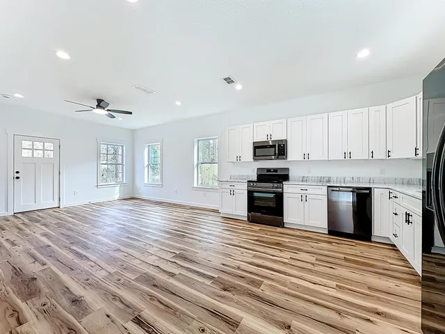 a large kitchen with granite countertop a stove top oven a sink dishwasher and a refrigerator with wooden floor