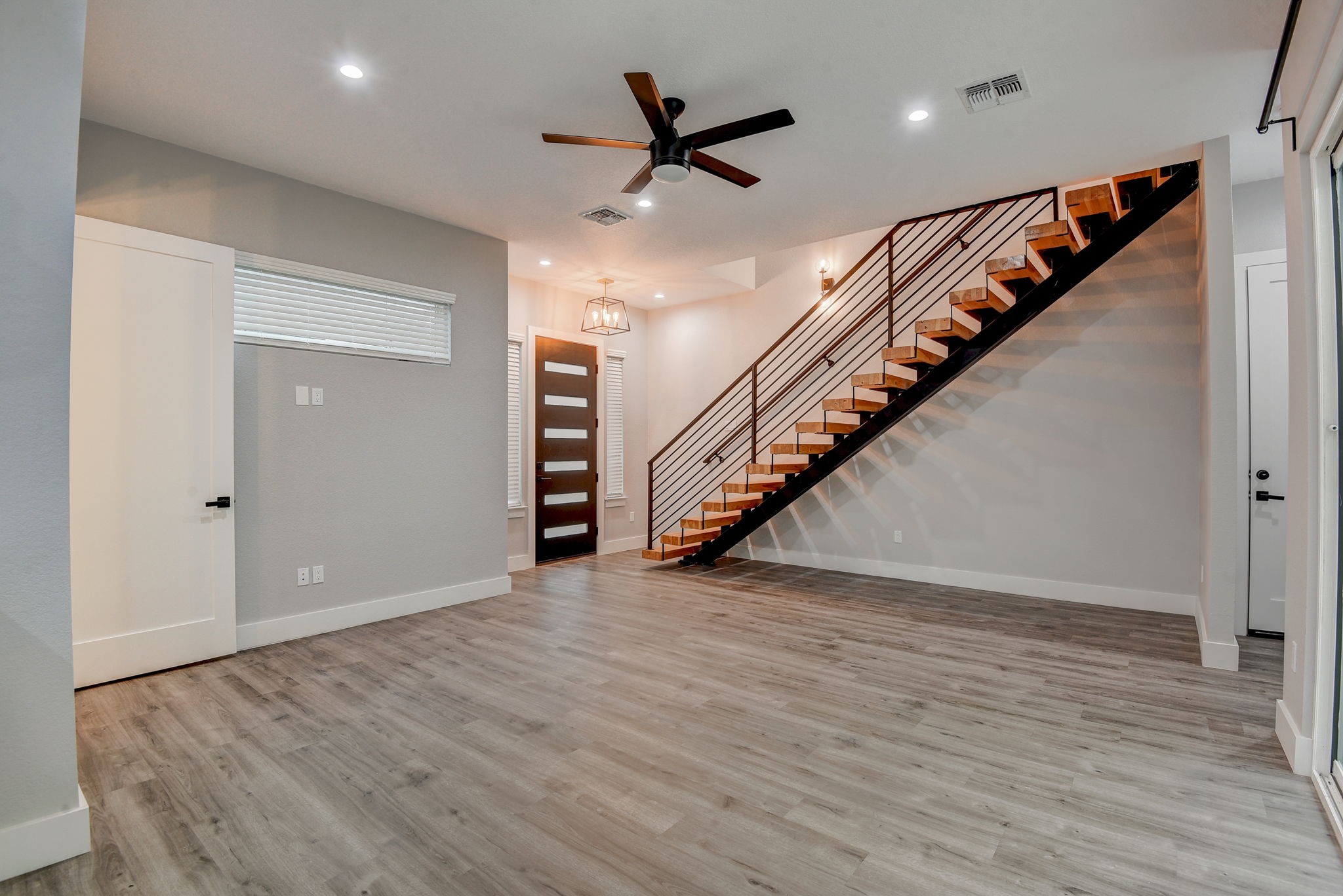 2507 Rogge Lane, Unit 2 Austin, TX 78723 - Photo 8 of 30 an empty room with wooden floor stairs and a ceiling fan
