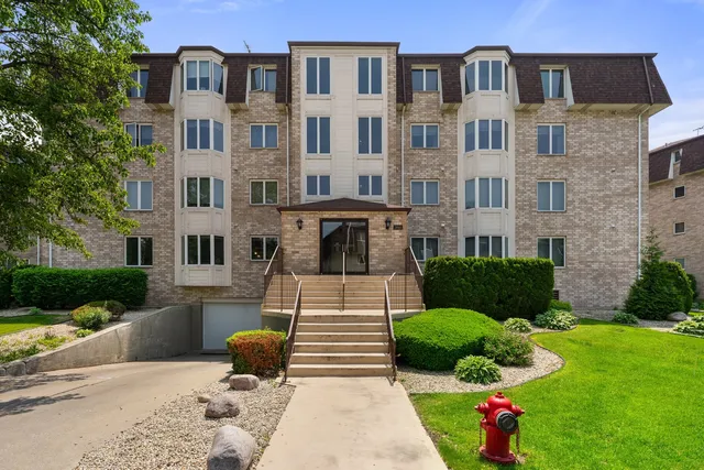 a front view of a multi story residential apartment building with yard and green space