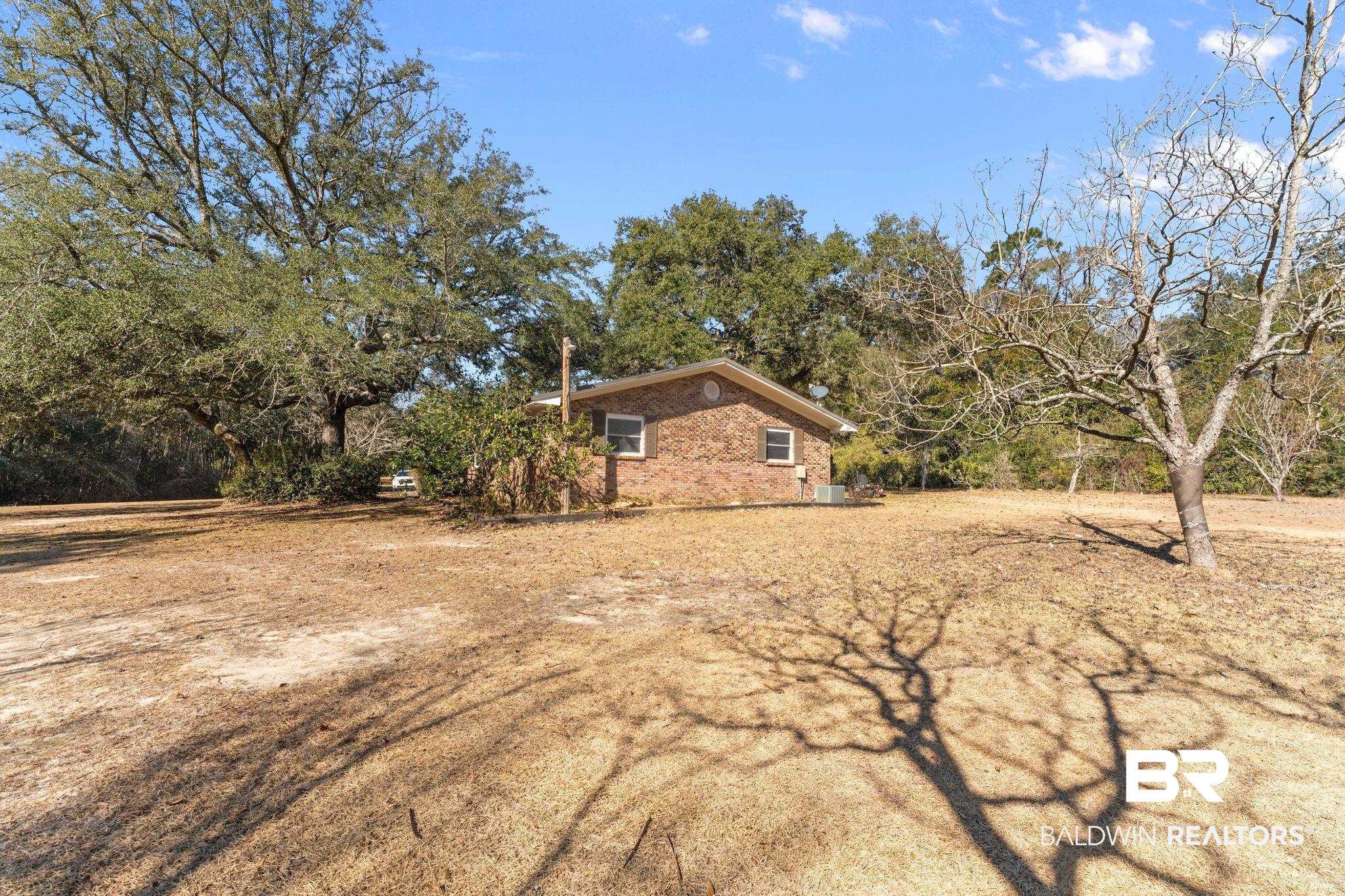 32989 Antietam Road Lillian, AL 36549 - Photo 51 of 56 View of side of property with brick siding and view of scattered trees