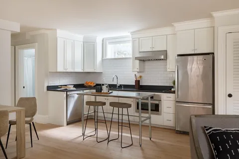 a kitchen with a refrigerator a stove a sink and chairs