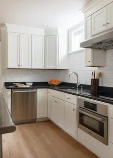 a kitchen with granite countertop white cabinets and stainless steel appliances