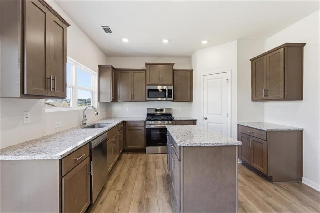 129 Bloomfield Circle Canton, GA 30114 - Photo 13 of 36 a kitchen with stainless steel appliances granite countertop a stove top oven a sink dishwasher and a refrigerator with wooden floor