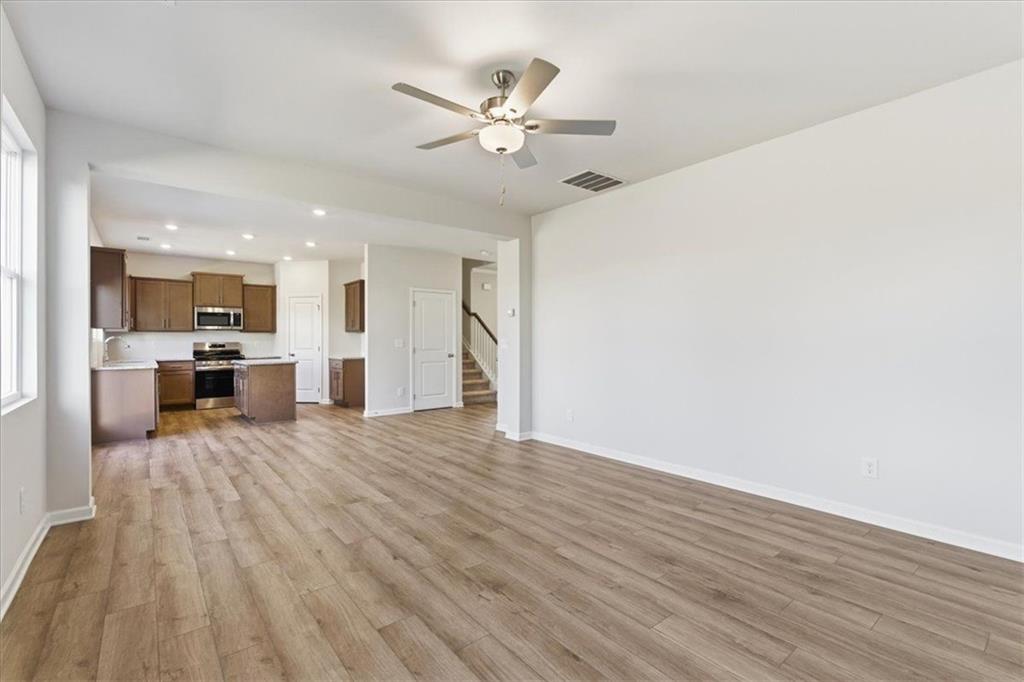 129 Bloomfield Circle Canton, GA 30114 - Photo 8 of 36 a view of a livingroom with a kitchen island wooden floor and a ceiling fan