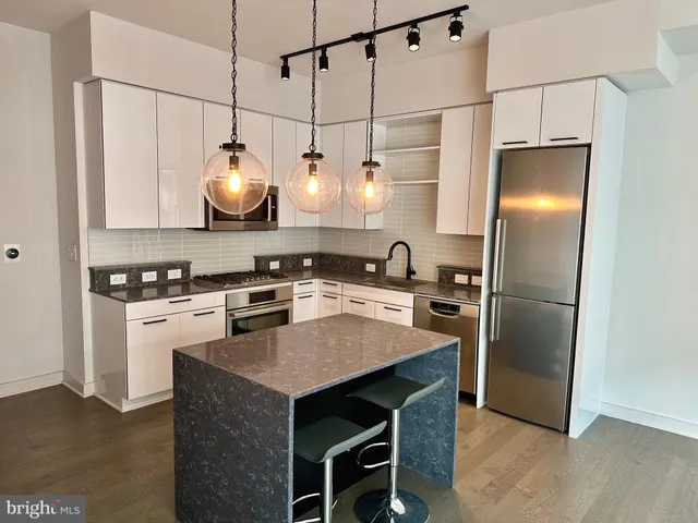 a kitchen with stainless steel appliances granite countertop a sink a stove a refrigerator and island