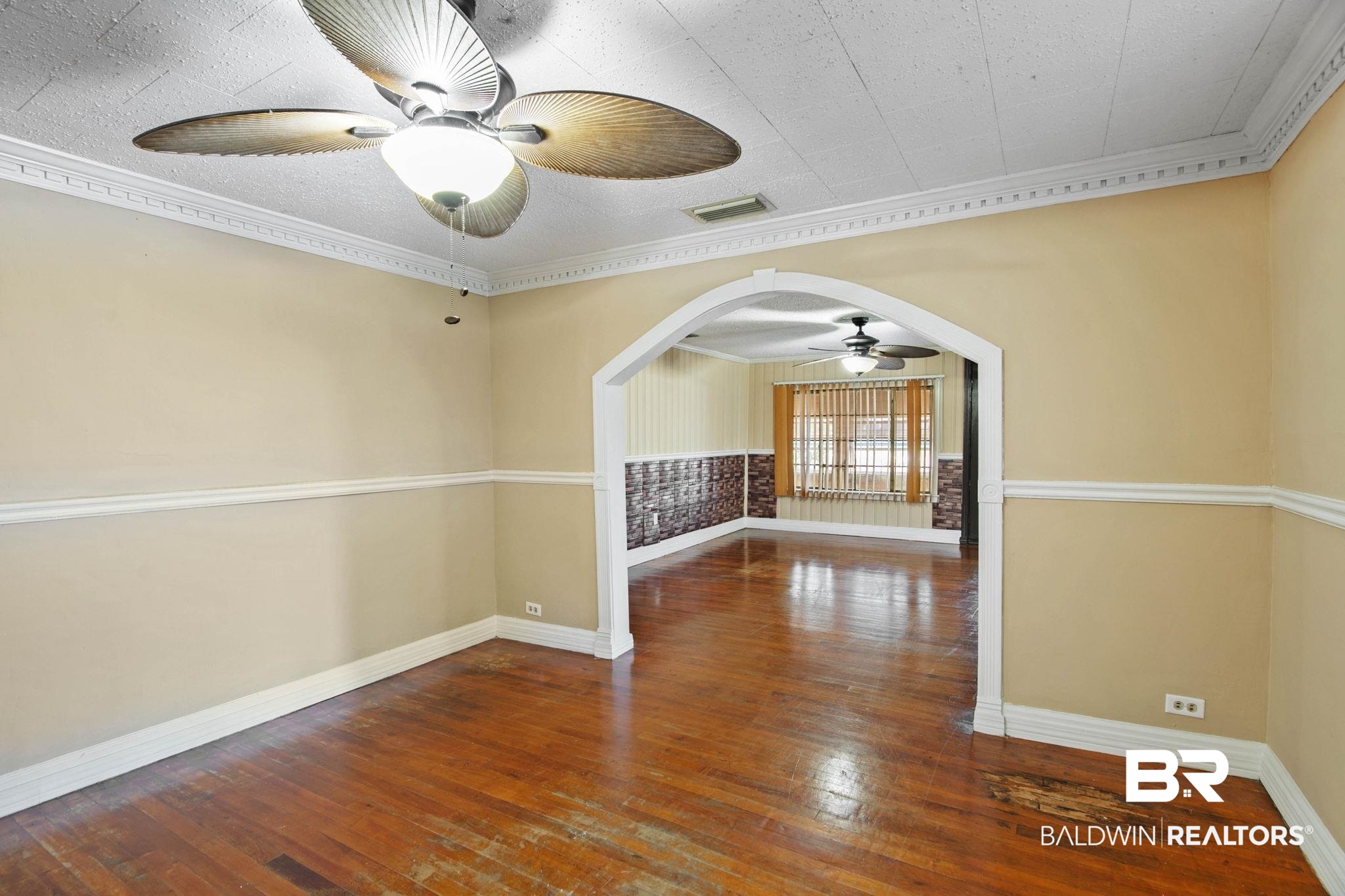 23240 County Road 47 Perdido, AL 36562 - Photo 10 of 29 Empty room featuring dark wood finished floors, ornamental molding, arched walkways, and ceiling fan