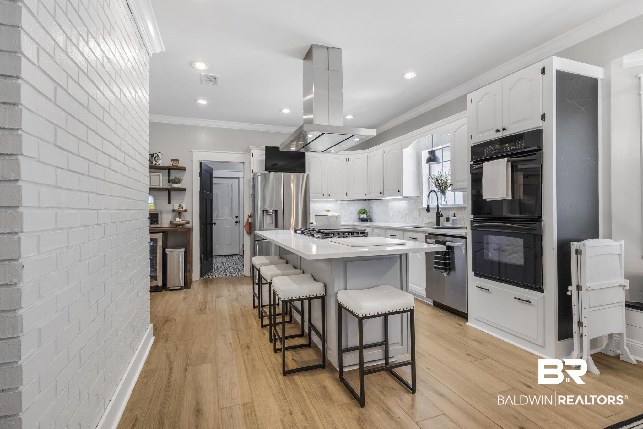 83 Caisson Trace Daphne, AL 36527 - Photo 18 of 63 Modern kitchen featuring light wood-finish flooring, white cabinetry, stainless steel appliances, a center island with bar seating, and recessed lighting