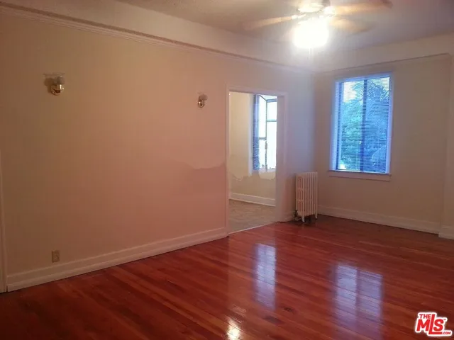 a view of an empty room with wooden floor and a window